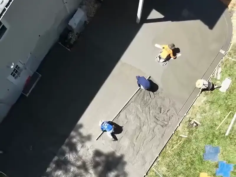Crew screeding a curved backyard concrete patio pour, seen from above